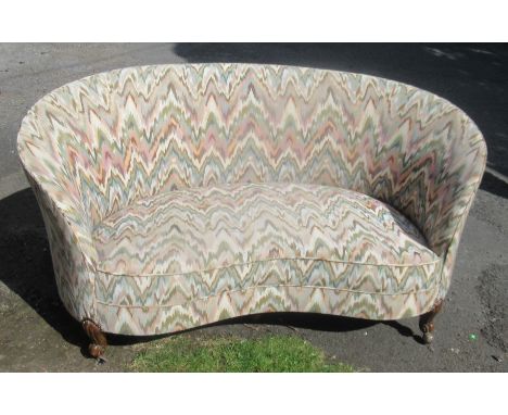 An upholstered curved settee, on carved legs