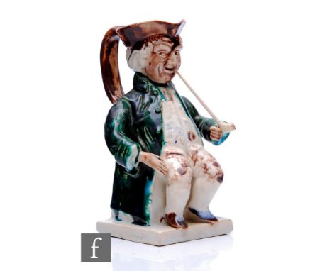 An early 19th Century Toby jug modelled as a seated gentleman in tricorn hat, frock coat, waistcoat and breeches and smoking 
