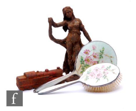 A two piece enamelled back floral patterned mirror and brush set, a cast iron figure of a maiden and a cast iron model of a t