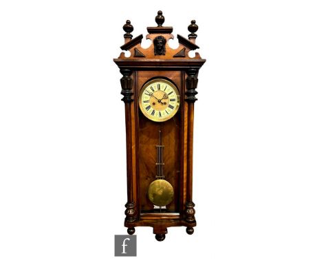 A late 19th Century walnut cased regulator wall clock, the spring driven movement enclosed by a glazed door below a mask and 