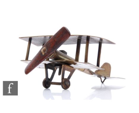 A Trench Art brass model of a biplane, wooden propeller and bullet made fuselage, the wing engraved 'Souvenir De La Guerre', 