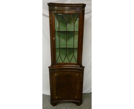 Mahogany corner cabinet of concave form with hinged glazed door on bracket feet