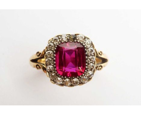 A yellow metal, diamond, and synthetic ruby ring, with central cushion-cut synthetic-ruby, framed by diamonds, crown-set and 