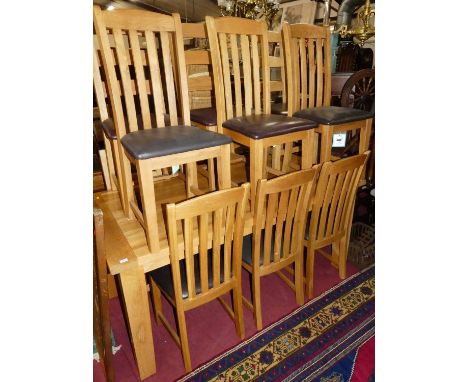 A contemporary light oak extending dining table, having pull-out action and single fold-out leaf, on square block supports, m