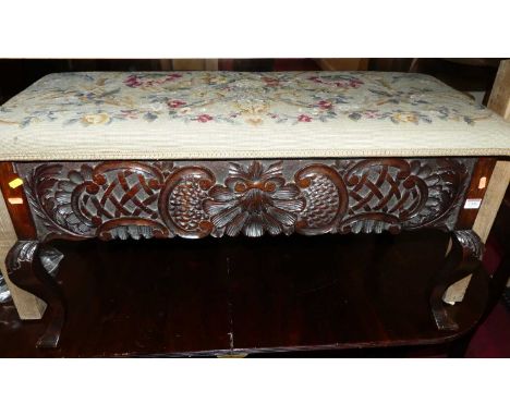 An early 20th century floral relief carved oak and floral tapestry upholstered hinge-top twin music seat, raised on pronounce