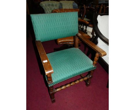 An early 20th century oak and green fabric studded upholstered pad back and seat open elbow chair, on bobbin turned supports,