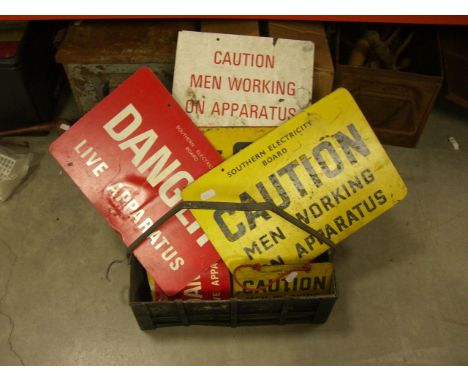 A quantity of vintage work safety signs and a rustic bottle carrier.
