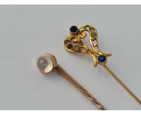 Two gold stick pins one with moonstones