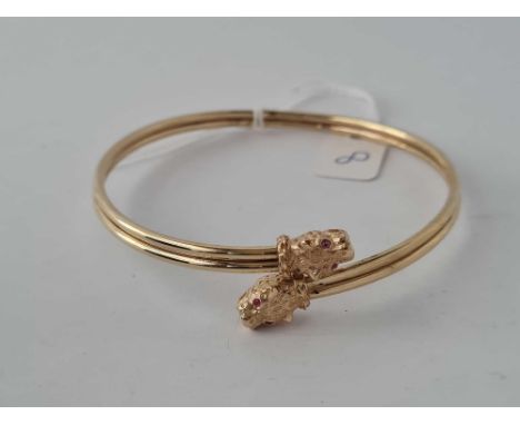 A TORQUE 9CT BANGLE with Leopard head terminals and ruby eyes  8.6g