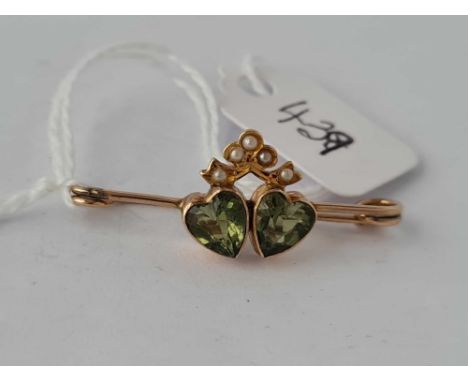 A vintage peridot and pearl double heart brooch set in gold