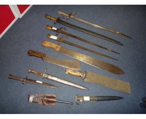 A LARGE BOX CONTAINING A NUMBER OF MILITARY BAYONETS, to include a large brush knife, a small brush knife, Belgium Army socke