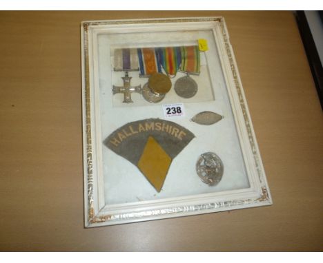 A GLAZED FRAME CONTAINING A GROUP OF FOUR MEDALS, original dog tag, cap badge (York and Lancaster) and 'Hallamshire' shoulder