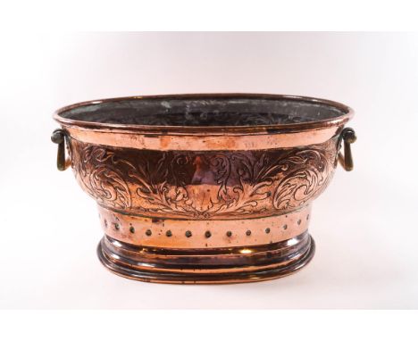 A Victorian oval copper planter with brass handles, hammered foliate scroll design in relief and punched circular decoration 