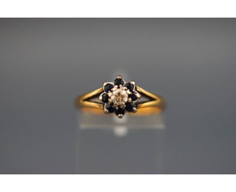 An 18 carat gold cluster ring set with 8 sapphires and a central diamond. Hallmarked 18ct, London, 1977 'CRF' 3.9 grams