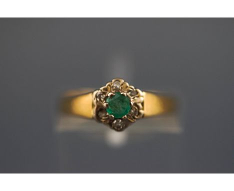 An 18 carat emerald and diamond seven stone cluster ring. Hallmarked 18ct, Birmingham. 2.5 grams, boxed