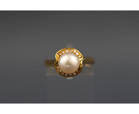 A yellow metal cluster ring set with a cultured pearl measuring 8.2mm. Further set with fourteen round brilliant cut diamonds