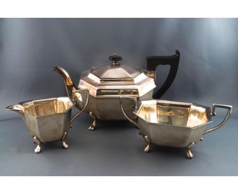 A silver three piece tea service, of canted rectangular form, each piece standing on four flared feet, the teapot with ebony 