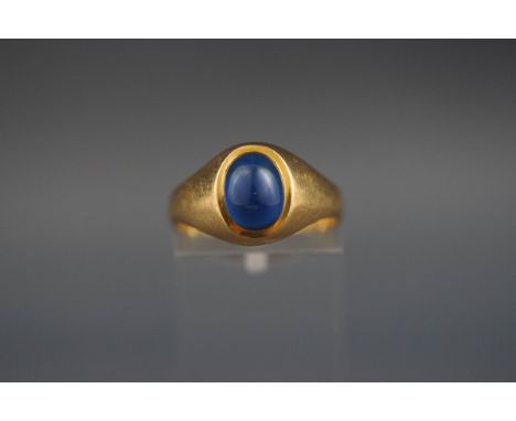 A yellow metal single stone cabochon ring set with blue glass. Stamped 18ct. 3.1 grams