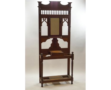 A Victorian oak hall stand with inset central mirror framed by spindle and fretwork decoration above lidded storage box and s