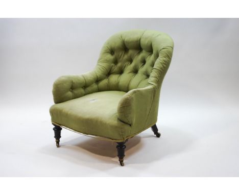 A Victorian button back armchair with turned ebonised legs and brass casters