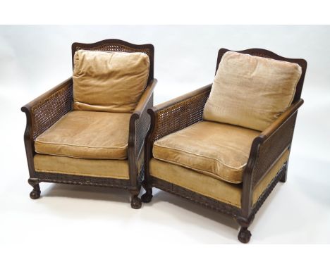 An early 20th century mahogany bergere suite, comprising a two seat sofa and a pair of armchairs, each with carved decoration