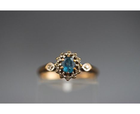 A hallmarked 9ct gold cluster ring set with an oval aquamarine measuring 4.70mm x 4.20mm. Further set with fourteen single cu