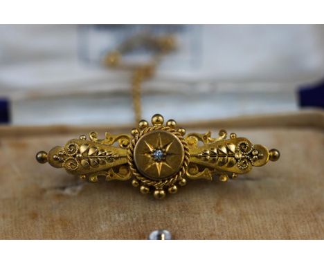 A Victorian 15 carat gold brooch, in case. Bead and filigree decoration centrally set with an old brilliant cut diamond measu