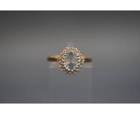 A hallmarked 9ct gold cluster ring set with a central oval aquamarine, surrounded by diamonds. Gross weight: 2.2 grams