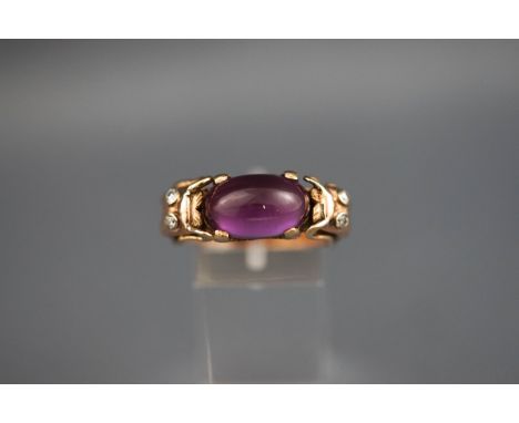 A yellow gold ring set with a synthetic colour change cabochon corundum and diamonds. Stamped 14K. 10.0 grams