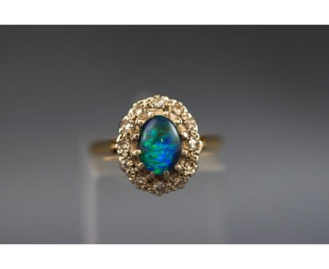 A hallmarked 18ct gold cluster ring set with an oval opal triplet and surrounded by twelve single cut diamonds measuring appr