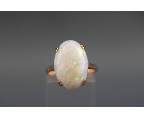 A yellow metal single stone ring set with an oval cabochon opal measuring approximately 18.8mm x 12.7mm x 5.90mm. Tests indic