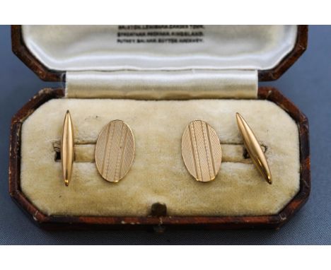 A boxed pair of hallmarked 9 carat gold oval cufflinks with engine turned design. T-bar and chain fittings. Hallmarked 9ct go