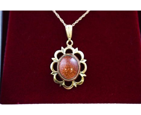 A hallmarked 9 carat gold pendant set with an oval cabochon cut sunstone measuring approximately 10.5mm x 8.70mm. Suspended f