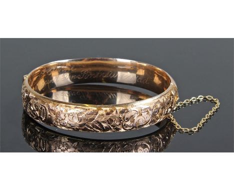 15ct gold bangle bracelet, chased with stylised foliate and floral decoration and complete with a safety chain, approximately