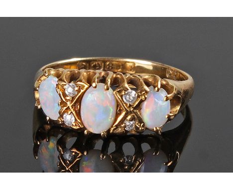 Opal and diamond ring, the three opal cabochons divided by two small diamonds in an open claw setting and mounted in 18 carat