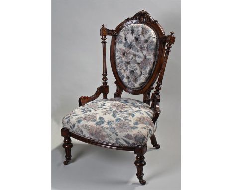 Victorian mahogany nursing chair. A carved arched back with button back upholstered pad, a pair of turned columns above a stu