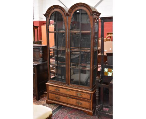 A 'Queen Anne' walnut double-dome cabinet, astragal glazed doors enclosing four shelves, the 18th century plinth base with tw