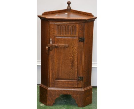 A Priory style oak floor standing corner cupboard of small proportions, finialled gallery, canted angles, sinle door enclosin