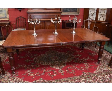A Victorian Mahogany wind-out dining table, having a rectangular top with canted corners, turned and reeded legs, ceramic cas
