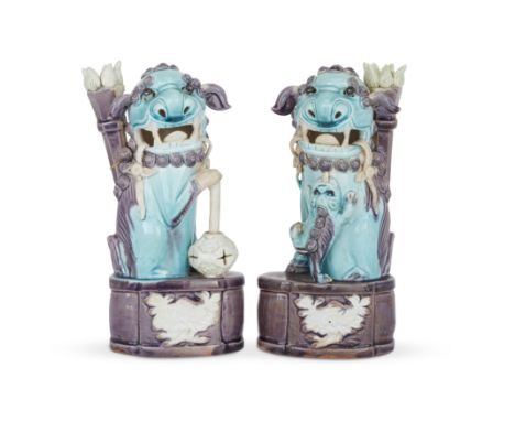 A pair of Chinese biscuit porcelain Buddhist lion incense stick holdersLate Qing dynastyEach modelled seated on an oval base,