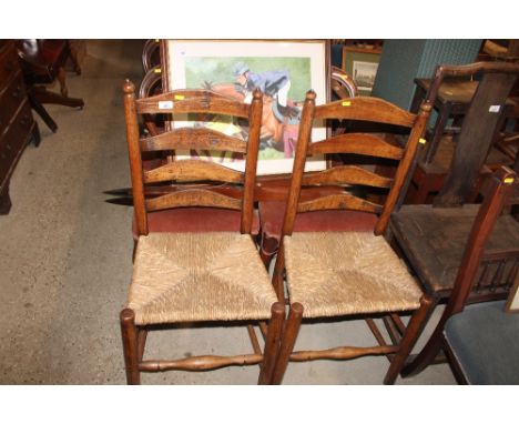 A pair of antique elm and rush seated ladder back dining chairs