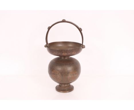 An Indian brass container with loop handle and chased enamel decoration 