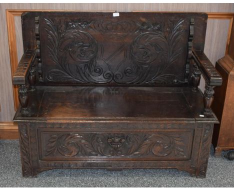 A 19th century carved oak monks' bench, with hinged seat and carved front panel