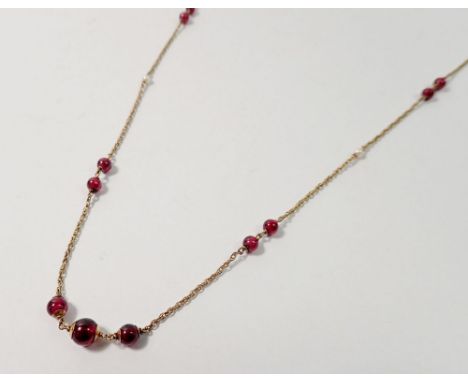 A 9 carat gold chain interspersed with garnets and seed pearls, 8.5g, 76cm long 