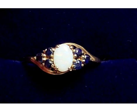 A 9 carat gold ring set opal flanked by six sapphires, size M, 1.1g 