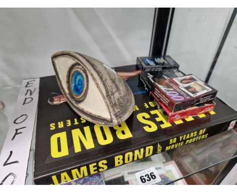 A BOOK OF JAMES BOND POSTERS, FOUR PACKS OF PLAYING CARDS AND A TROIKA TYPE POTTERY MODEL EYE