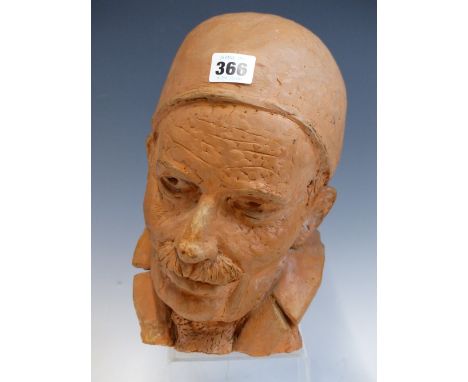 A SCULPTED TERRACOTTA HEAD OF A MOUSTACHIOED MAN WEARING A SKULL CAP.   H 26cms.