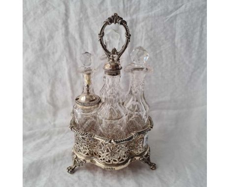 A decorative Victorian six bottle cruet with pierced sides, three claw feet and ring handle, cut glass bottles, Sheffield 186