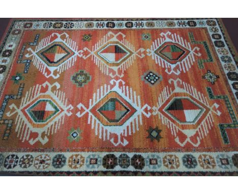 A vintage West German carpet, geometric and floral medallions on a orange, pink and light brown field, within geometric borde