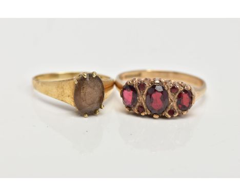 A 9CT GOLD GARNET RING AND A YELLOW METAL SMOKEY QUARTZ RING, the first ring designed with three oval cut garnets, interspace